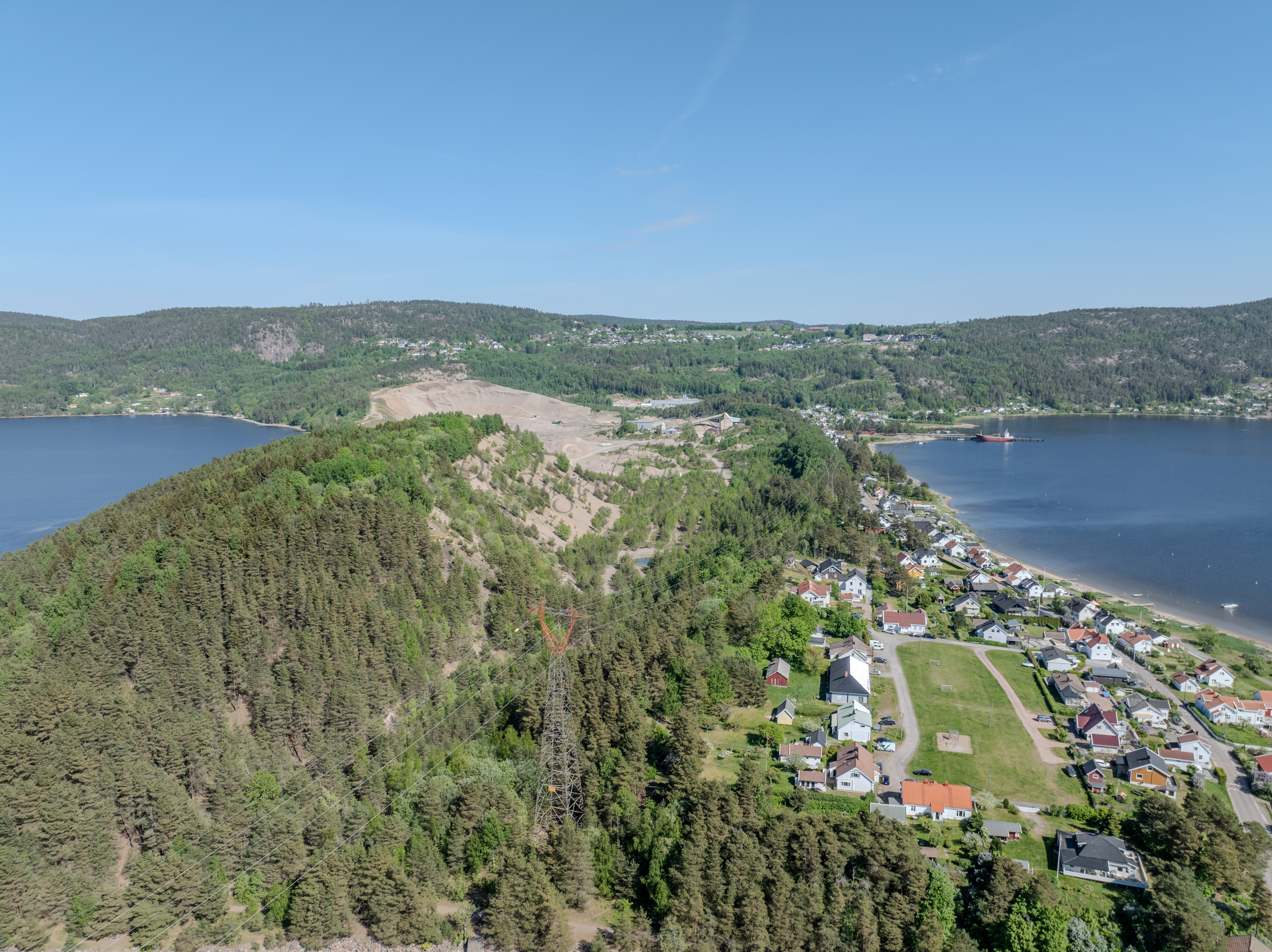 Buildings on both sides of a fjord where a ferry and other smaller boats are sailing