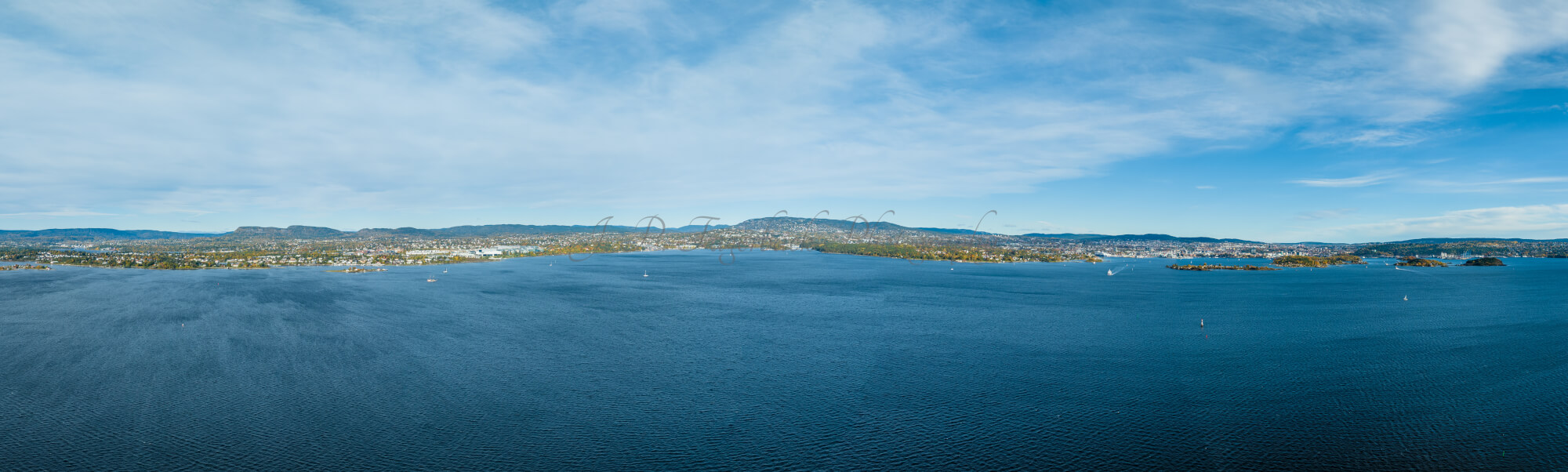 Large body of water with a coast line in the  background under a blue sky