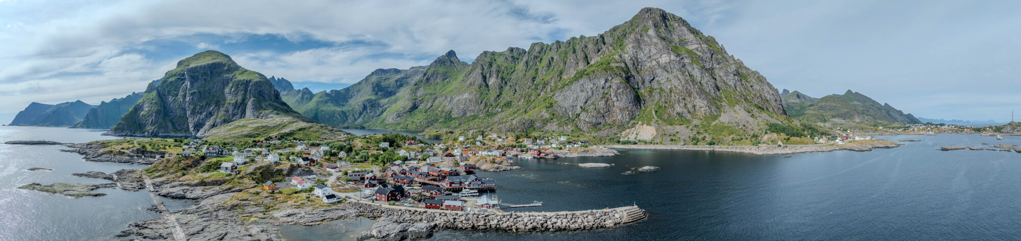 Buildings along the shore of a body of water with a mountain in the background on a gray day