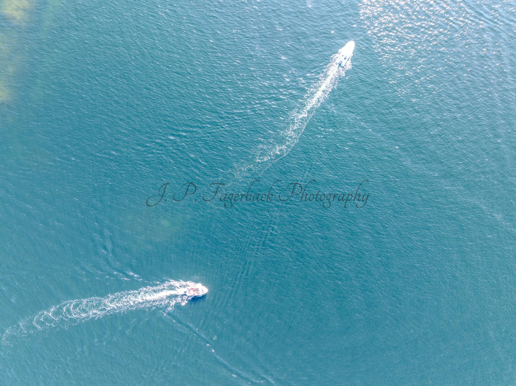 Boats in a blue sea making wakes