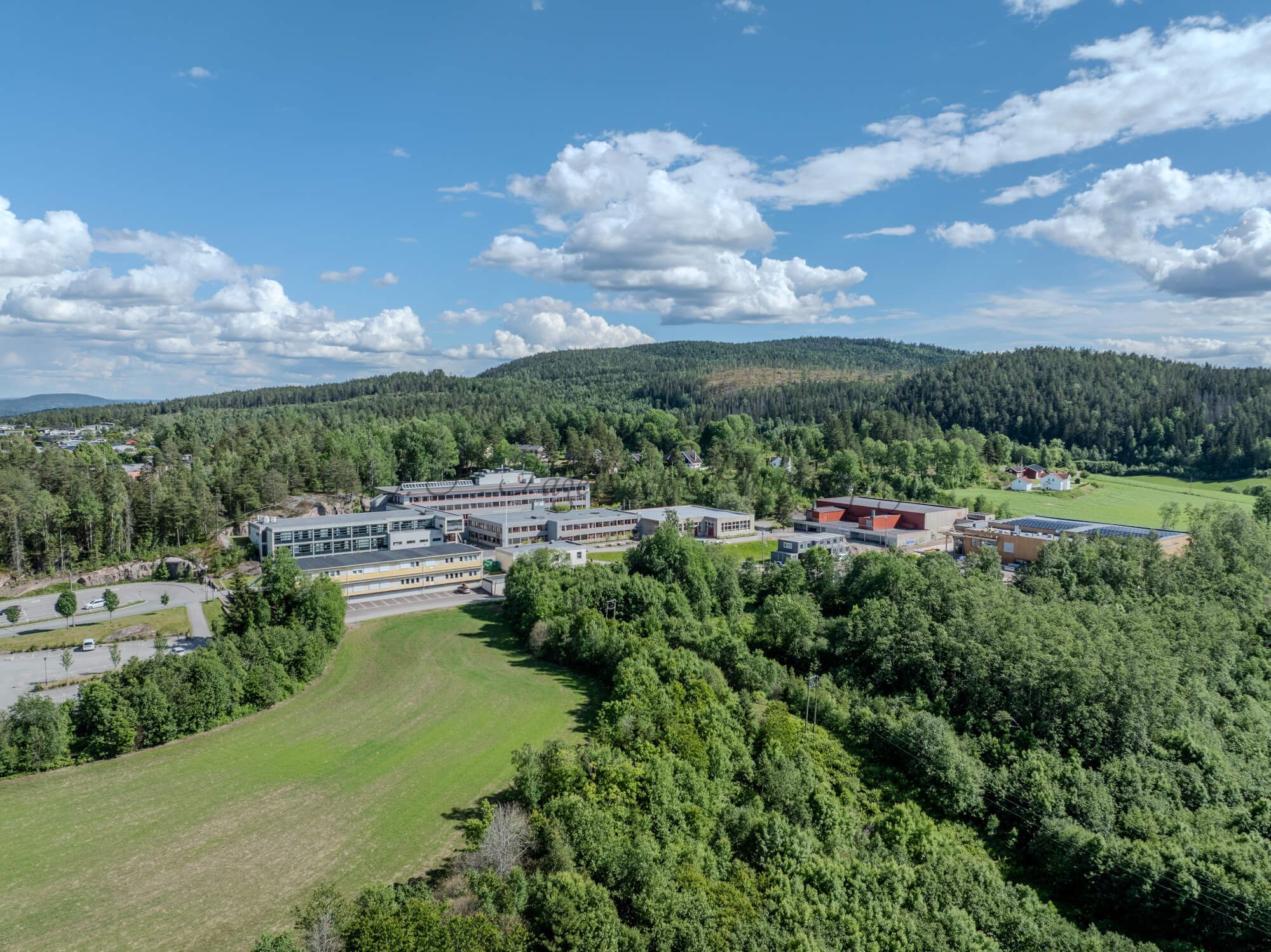 Buildings in a wooded green area under a partially clouded blue sky